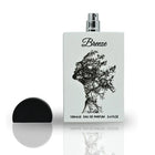 The image displays a perfume bottle named "Breeze" by Lattafa. The bottle has a flat, flask-like shape with a silver spray nozzle and a black cap beside it. It features a creative black print of a woman's profile, depicted with tree branches against the w