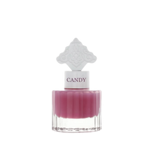  The image features a perfume bottle with a clear base and a purple-colored liquid. It has a white cap with the word "CANDY" printed on it in purple, matching the liquid's color. The cap is topped with a white ornate design that resembles an intricate architectural pattern, possibly inspired by Middle Eastern art.