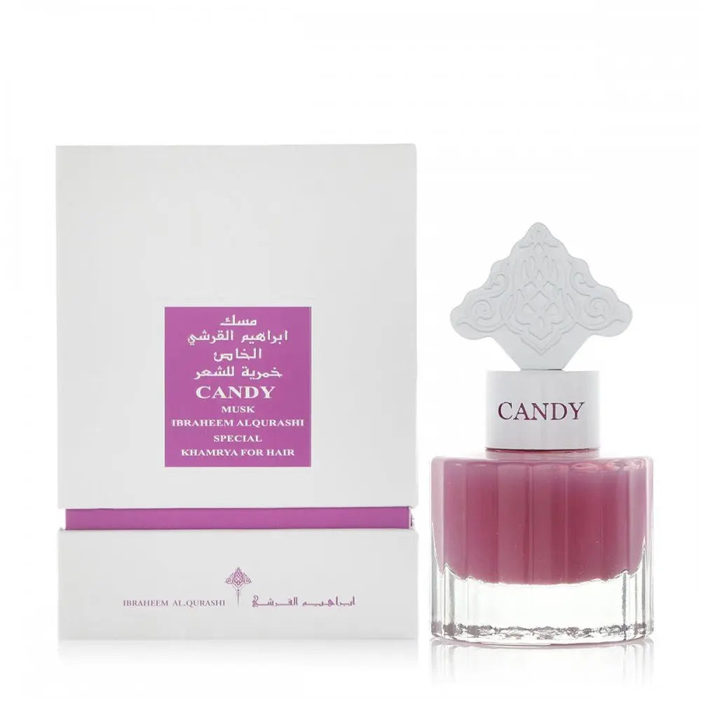  The image displays a perfume or hair mist product with a bottle and packaging. The bottle has a clear bottom and a purple-colored upper half, with a white ornate cap reminiscent of Middle Eastern or Islamic art patterns. The front of the bottle has the word "CANDY" in uppercase letters. The white packaging box has a purple label with gold and white text that reads "CANDY MUSK IBRAHEEM AL QURASHI SPECIAL KHAMRIYA FOR HAIR" alongside Arabic script. 