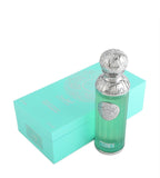The image shows a perfume bottle named "Capri" from the Gissah collection, placed next to its packaging. The perfume bottle is cylindrical with a teal glass body and a decorative silver cap featuring intricate embossed patterns. A silver medallion with an ornate design is affixed to the front of the bottle. The packaging is a matching teal box with a mandala-like design and the names "Gissah" and "Capri" printed on it.