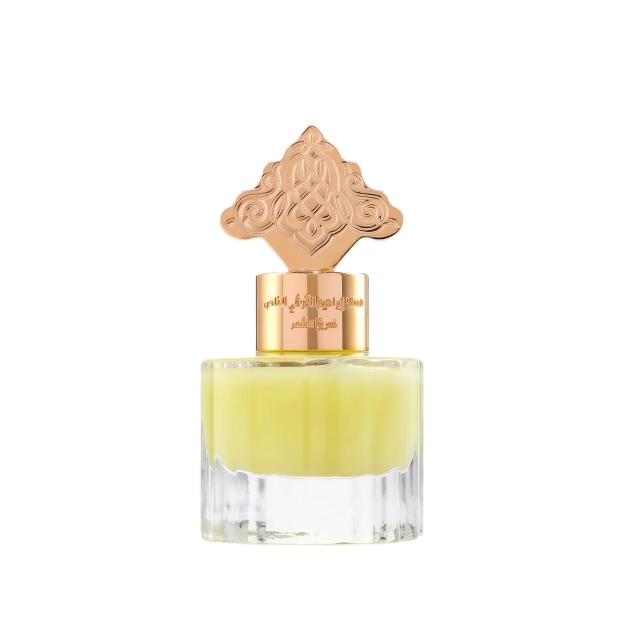 The image depicts a transparent perfume bottle with a yellow-colored liquid. The bottle is topped with a gold cap that has an ornate design, which may draw inspiration from Middle Eastern or Islamic art. The neck of the bottle features gold lettering in Arabic, likely indicating the name of the fragrance or the brand. The cap and the color of the liquid give the product a luxurious and exotic appearance, suggesting that it may be a cardamom-scented musk designed for use on hair.