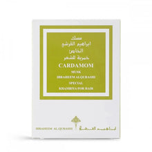 The image shows a white packaging box with a green label for a fragrance product. The label has both English and Arabic text, reading "CARDAMOM MUSK IBRAHEEM AL.QURASHI SPECIAL KHAMRIYA FOR HAIR." The design of the box is simple and elegant, with the brand's logo at the bottom. The color scheme and product name suggest a hair fragrance with cardamom scent notes.