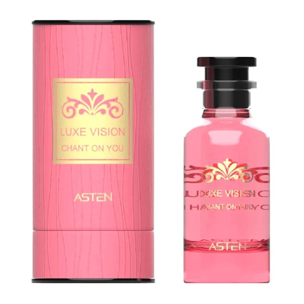 A pink, cylindrical perfume box with a gold-accented Luxe Vision Chant On You label beside a matching pink glass perfume bottle adorned with a decorative gold motif
