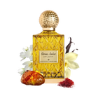 The image depicts a perfume bottle with a golden yellow liquid, named "Citrine Amber." The bottle has a textured gold cap and a label with the name in both English and Arabic script. Surrounding the bottle are a piece of amber resin, a few saffron threads to the right, vanilla pods to the upper right, and white flowers to the left, likely to represent some of the scent notes in the fragrance.
