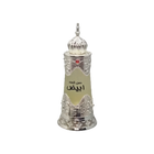 The image depicts a traditional Arabic-style perfume bottle. The bottle is cylindrical with a tapered base and features intricate silver metallic filigree work around the top and bottom, giving it an ornate and luxurious look. The central portion of the bottle is a frosted glass with a label that includes Arabic script, likely denoting the name of the perfume. At the top of the bottle sits a decorative silver dome-shaped cap with a pointed finial, adorned with a red gem at its center. 