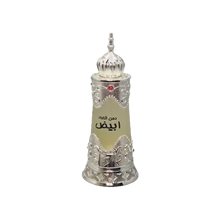 The image depicts a traditional Arabic-style perfume bottle. The bottle is cylindrical with a tapered base and features intricate silver metallic filigree work around the top and bottom, giving it an ornate and luxurious look. The central portion of the bottle is a frosted glass with a label that includes Arabic script, likely denoting the name of the perfume. At the top of the bottle sits a decorative silver dome-shaped cap with a pointed finial, adorned with a red gem at its center. 