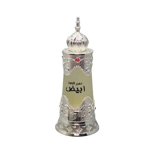 The image depicts a traditional Arabic-style perfume bottle. The bottle is cylindrical with a tapered base and features intricate silver metallic filigree work around the top and bottom, giving it an ornate and luxurious look. The central portion of the bottle is a frosted glass with a label that includes Arabic script, likely denoting the name of the perfume. At the top of the bottle sits a decorative silver dome-shaped cap with a pointed finial, adorned with a red gem at its center. 