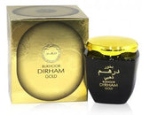 A black jar with a glossy golden lid labeled "Bukhoor Dirham Gold" in Arabic and English script, placed next to a circular golden box with the same label. The box has intricate patterns around the edges, suggesting that this product is a luxury bakhoor incense, which is used to perfume homes and clothing, commonly found in the Middle Eastern region.