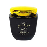 A black jar with a shiny golden lid, with "Bukhoor Dirham Gold" written in white Arabic and English script on the front. The contrast between the black jar and the gold lid suggests a product that is both traditional and luxurious, commonly used in Middle Eastern cultures as a form of incense known as bakhoor.