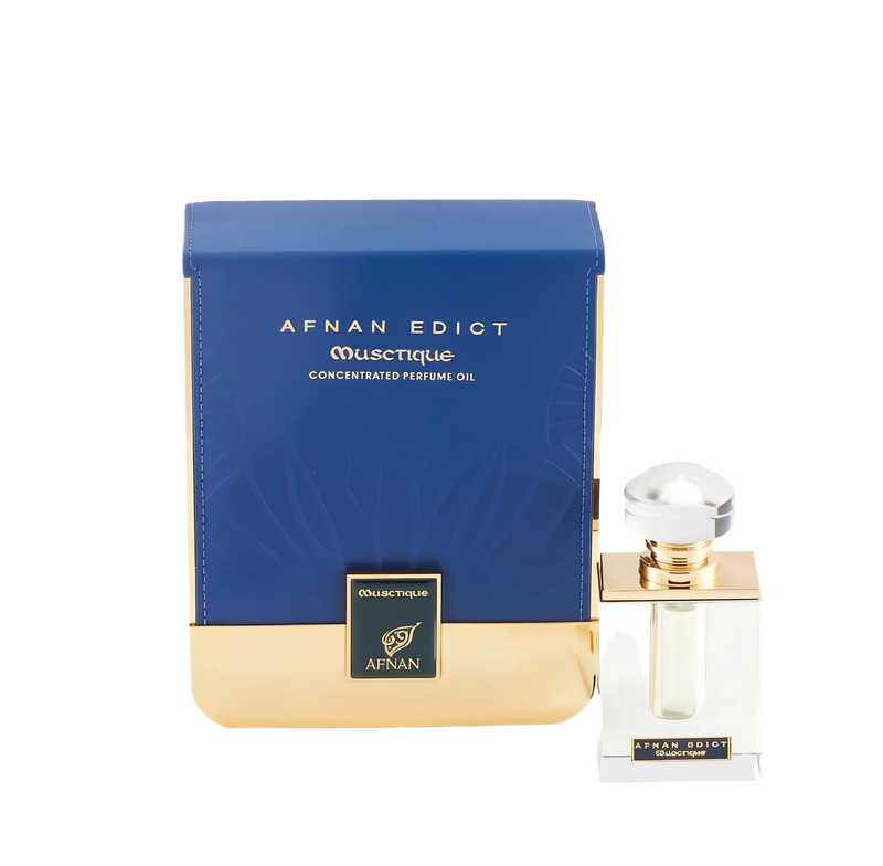 The image shows a perfume product with its packaging. The perfume bottle is clear with a square base and features a golden band around the neck, topped with a large, round, clear cap. The front label is minimalistic, with the name "AFNAN EDICT OUSCTIQUE" in a simple font. Next to the bottle is its box, which is predominantly navy blue with a textured pattern and a broad golden base.  The combination of navy blue and gold suggests a luxurious and sophisticated product.
