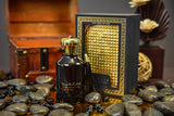 This image shows a dark, amber-colored perfume bottle with "Fakhar Al Oud" written in white Arabic script, accompanied by a tassel hanging off its golden cap. The bottle is displayed in front of its box, which is adorned with a golden lattice pattern and the phrase "THE PRIDE OF OUD". The setting includes smooth black stones scattered around, and there are elements of wood and a feathered texture in the background, evoking a sense of natural luxury.