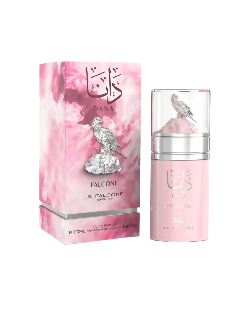 A pink rectangular perfume box featuring Arabic calligraphy and labeled ‘Dana Falcone’ by Le Falcone stands beside a matching cylindrical pink bottle with a clear cap, showcasing a silver falcon perched on a pink rock.