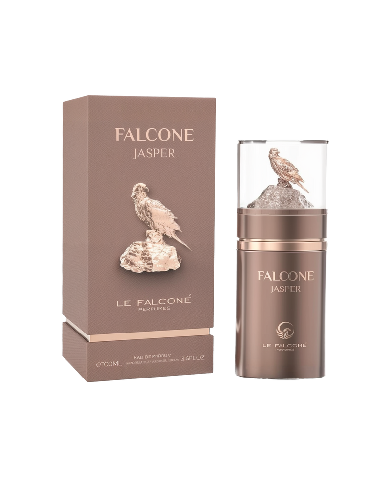 A brown rectangular perfume box labeled ‘Falcone Jasper’ by Le Falcone stands beside a matching cylindrical brown bottle with a clear cap showcasing a gold falcon perched on a metallic brown rock.