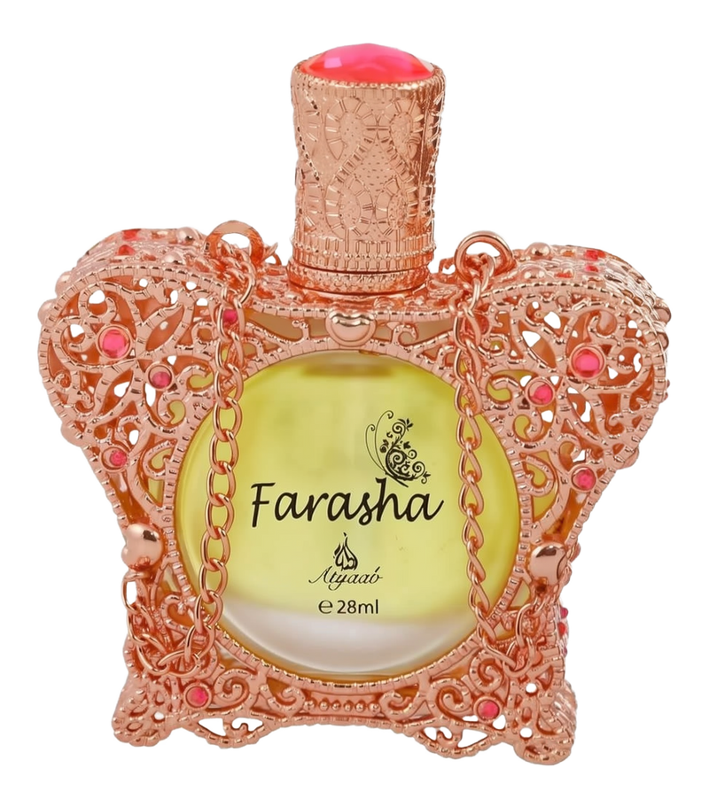 A close-up of an ornate perfume bottle with a rose gold lace-like design embellished with pink gemstones. The bottle cap is textured and also in rose gold, with a peach-colored top. It contains a yellow liquid, and the front of the bottle has the name "Farasha" printed in black, with a small butterfly motif above it, and "Ayyashi e 28ml" indicating the fragrance volume.
