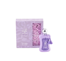 The image shows a bottle of "Fatima Velvet Love" extrait de parfum by Zimaya alongside its packaging. The perfume bottle is a soft lavender color with a silver spherical cap and is adorned with matching lavender tassels.   The accompanying box is also lavender with silver text and a clear window showcasing lavender rose petals inside, enhancing the luxurious and feminine presentation of the product.
