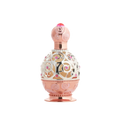 The image depicts an ornate perfume bottle on a white background. The bottle features a rose gold base and cap with intricate swirl patterns embossed on the surface. A decorative metal overlay with filigree designs encases the clear central portion of the bottle, adorned with small pink gemstone accents. The cap is topped with a pink crystal-like element, adding to the luxurious appearance of the bottle.