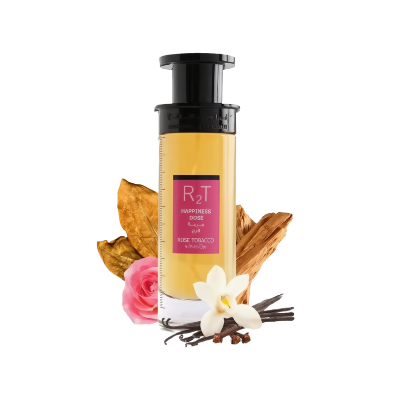 This is an image of a cylindrical clear perfume bottle with a black pump and a yellowish liquid inside, labeled "RT Happiness Dose" with additional text in Arabic and "ROSE TOBACCO" underneath. The bottle is positioned against a white background with a pink rose, a dry tobacco leaf, a cluster of vanilla beans, a white orchid flower, and some cinnamon sticks arranged around it, indicating the scent notes of the perfume.