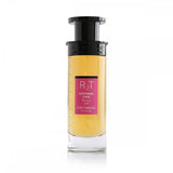 This is an image of a cylindrical clear perfume bottle with a black top and pump. The perfume has a yellow tint and features a pink label with the initials "RT" in large letters, the phrase "HAPPINESS DOSE" in smaller letters, both in English and Arabic, and "ROSE TOBACCO" underneath. The bottle is showcased against a plain white background, focusing on the simplicity and elegance of the design.