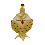 he image displays an opulent perfume bottle with a white background. The body of the bottle is a pale, translucent yellow, topped with a bright red cap resembling a gemstone. The bottle is adorned with a golden overlay featuring intricate cut-out patterns and red gemstone accents. Arabic script is prominently displayed in the center, with smaller text below.