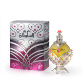 A round perfume bottle with a yellowish-green liquid, adorned with intricate silver and pink detailing, including a red teardrop-shaped gemstone at the center and a silver cap with a pink top, displayed next to a silver box with pink and silver patterns and Arabic text.