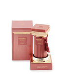 The image shows a luxurious perfume product. The perfume bottle is placed on a podium-like stand with a reflective golden surface. The bottle is cylindrical with ribbed texture and a rich, rosy pink hue. It features a golden cap adorned with a decorative tassel in a matching rosy pink color. The label on the bottle reads "HISTORIC DORIA AFNAN". Beside the bottle is its packaging box, which follows the same color scheme and has vertical stripes, with the brand and perfume name printed on it. 