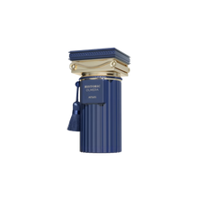 The image is of a luxurious fragrance bottle. The bottle is cylindrical and has a deep blue color with vertical ridges, reminiscent of Greek column designs. The cap is an elaborate gold-colored ornament with intricate details and a tassel hanging off its side. On the bottle, there is a gold label with the text "HISTORIC OLMEDA AFNAN" in bold letters. The product is set against a clean, neutral background that highlights its elegance and design details.