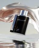 The image displays a sleek and contemporary perfume bottle floating against an artistic backdrop. The bottle has a shiny black glass exterior with a smooth, reflective silver cap. In the background, there is a fluid and dynamic metallic structure with a rose gold finish that swirls around the bottle, creating a sense of movement. Below the bottle, there appears to be a reflective surface, reminiscent of water, adding to the overall ethereal and high-end feel of the presentation. 