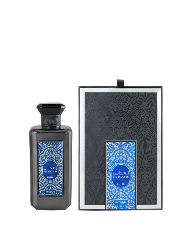 A bottle and packaging of Inekas Luna Eau De Parfum by Zimaya. The perfume bottle features a sleek, smoky black finish with a bold blue and silver ornamental label, and a black hexagonal cap with textured detailing. The matching box is black with embossed patterns and a central label that mirrors the bottle’s intricate blue design. The overall look is modern, mysterious, and luxurious, suggesting a fragrance with depth and sophistication.