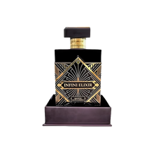 Infini Elixir by Maison Alhambra - a luxurious black perfume bottle with gold geometric patterns, displayed in a matching base. The bottle features a sophisticated rectangular design with a bold label at the center, highlighting the opulent and high-end nature of this fragrance. The set emphasizes elegance and exclusivity.