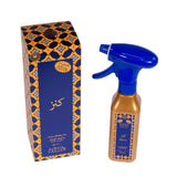 The image features a "Kanz" water-based air freshener set, including a spray bottle and its accompanying box. The box boasts an intricate geometric pattern with stars in shades of blue, orange, and white, with Arabic script and a clear label reading "Kanz" in a large, elegant font. The spray bottle is a metallic gold color with a blue spray nozzle, labeled with design elements that match the box. Arabic script is prominently featured on both the bottle and box, indicating a Middle Eastern or Arabic brand.
