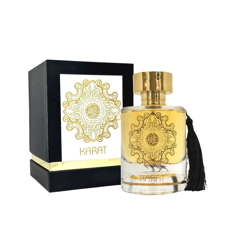 A product image of Lattafa’s “Karat” perfume: a clear cylindrical glass bottle filled with golden liquid, decorated with an intricate gold filigree medallion on its front and topped by a shiny gold cap.