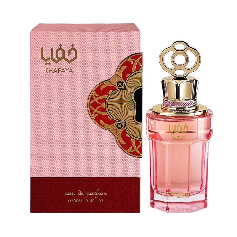 The image displays a rectangular, pink-hued perfume bottle with a golden cap featuring an intricate loop design, alongside its packaging box. The label on the bottle reads "?????" in Arabic script and "KHAFAYA" in Latin characters. The pink box has a detailed patterned background and a large maroon section at the bottom with the text "eau de parfum 100ml 3.4fl.oz." in gold lettering. A graphic design element with a red and gold flower motif extends from the left side of the box.