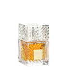 This image displays a square-shaped perfume bottle with a clear crystal-like design. The bottle has a substantial, geometrically cut glass structure that reflects light, enhancing the rich golden-yellow color of the perfume inside. The cap is a clear cube