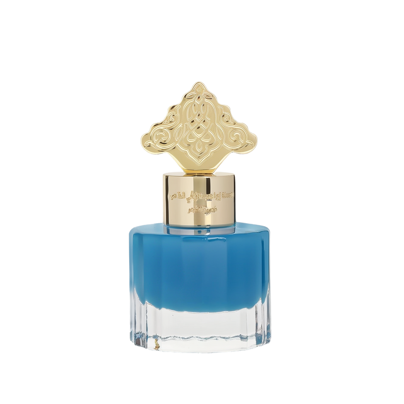 This image features a square-shaped perfume bottle with a blue gradient color, transitioning from a darker blue at the top to clear at the bottom. The cap is gold with intricate, ornate patterns resembling traditional Arabic designs. Arabic script is present on the gold band just below the cap, likely denoting the brand or fragrance name.