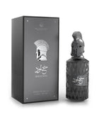 Le Falcone Niche Collection’s “Khulood” perfume against a white background: on the left, a closed matte-dark rectangular gift box with a glossy silver-tone front panel featuring the Le Falcone logo, a stylized warrior-helmet graphic, Arabic calligraphy and the word “Khulood,” plus “Extrait de Parfum 85?ml / 2.8?fl?oz” printed below. On the right, the box is opened to reveal the perfume bottle resting on a raised beige interior platform.