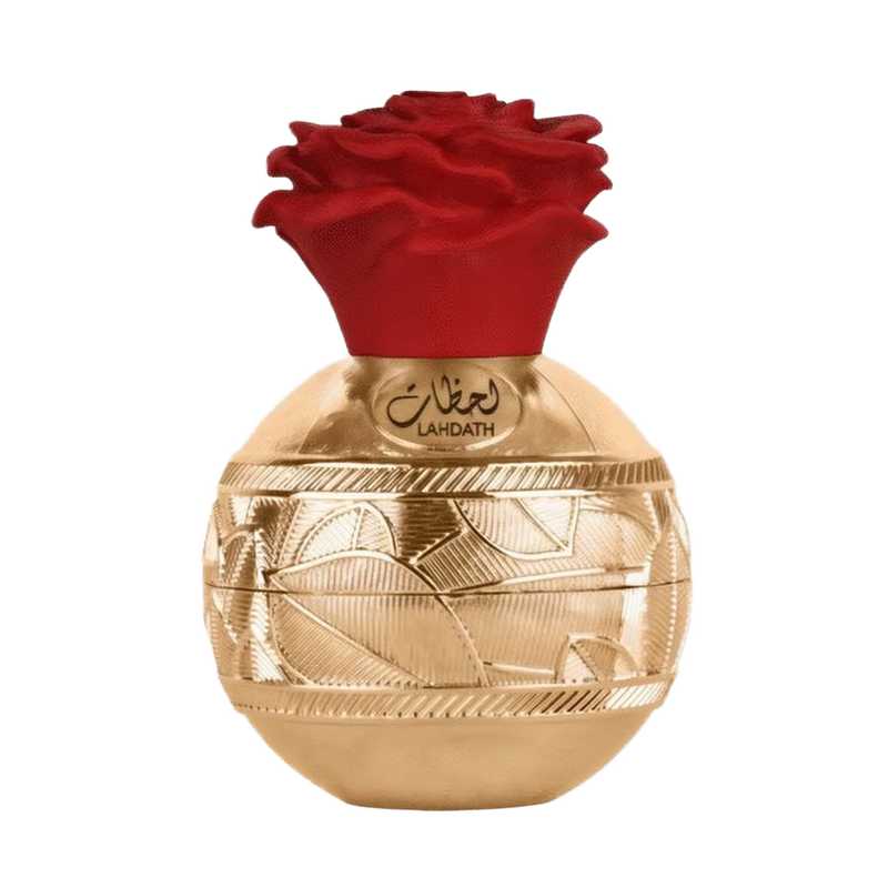 The image shows a luxurious perfume bottle with a golden spherical base featuring ornate, engraved patterns. A red, rose-shaped cap sits on top of the bottle, adding a vibrant contrast to the gold base. The front of the bottle has Arabic script reading "L