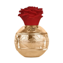The image shows a luxurious perfume bottle with a golden spherical base featuring ornate, engraved patterns. A red, rose-shaped cap sits on top of the bottle, adding a vibrant contrast to the gold base. The front of the bottle has Arabic script reading "L
