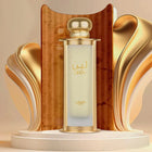 The image showcases the "Leen" perfume by Lattafa Pride, placed on a pedestal with an artistic backdrop. The cylindrical perfume bottle has a clear-to-gold gradient glass and is capped with a gold top. The name "LEEN" is prominently displayed in the cente