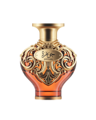A product shot of Le Falcone Niche Collection’s “Jawhara” perfume bottle against a white background: a heart-shaped amber glass vessel topped with a wide, gold-tone cap. The bottle’s upper half is wrapped in ornate gold filigree with elegant arabesque scrollwork, featuring an oval plaque engraved with Arabic calligraphy above the word “Jawhara.”