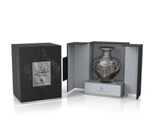 A product shot of Le Falcone’s “Sultan” niche-collection perfume: a matte black rectangular gift box with a silver plaque bearing Arabic script and the word “Sultan” sits closed on the left. On the right, the box is open to reveal an ornate, heart-shaped glass perfume bottle adorned with intricate silver filigree and a matching “Sultan” label, nestled on a light grey interior platform.