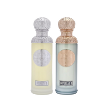 The image features two perfume bottles from the Gissah collection, "Hudson II" and "Imperial II." Both bottles have tall, cylindrical shapes with ornate silver caps featuring embossed designs. "Hudson II" has a light yellow tinted glass body with a silver medallion, and "Imperial II" has a light blue tinted glass body with a copper medallion. Each bottle is labeled with its respective name in elegant font at the bottom. 