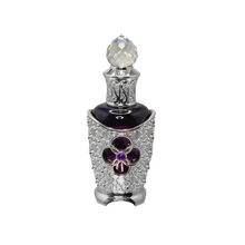 The image features an ornate perfume bottle. The bottle has a dark body with a silver filigree design encrusted with crystals, highlighting a prominent purple flower-shaped jewel at the center. It's topped with a faceted crystal cap that adds to the luxurious appeal. The intricate details suggest a bespoke and opulent scent contained within. The overall design of the bottle conveys a sense of vintage elegance and exclusivity.