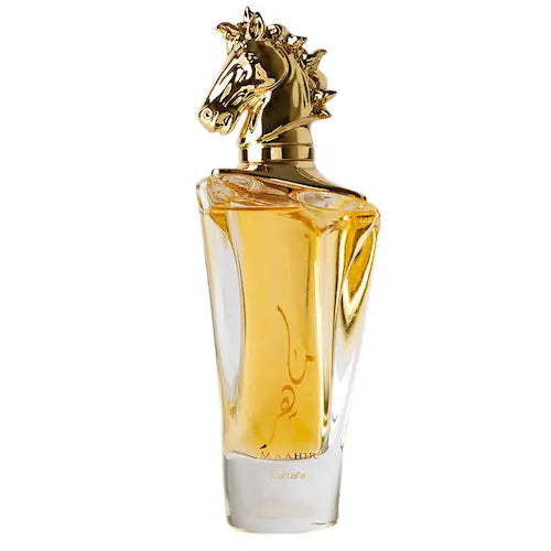 The image features a luxurious perfume bottle with a clear glass design showcasing a golden-colored fragrance inside. The bottle is adorned with a unique, detailed gold horse head sculpture as the cap, indicating a possibly equestrian-themed brand or inspiration. There is an Arabic calligraphy design on the front of the bottle, suggesting a name or brand related to the fragrance, with the word "Maahir" in smaller text at the bottom, possibly indicating the name of the perfume. 