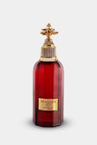 The image shows a bottle of "Magma Love" perfume by Zimaya. The bottle is deep red with a faceted design and a gold label that reads "MAGMA LOVE" and "zimaya" at the bottom. The cap is an ornate gold structure with a decorative, flower-like design on top, adding an element of luxury and sophistication. The overall design of the bottle is bold and elegant, conveying a sense of passion and opulence.
