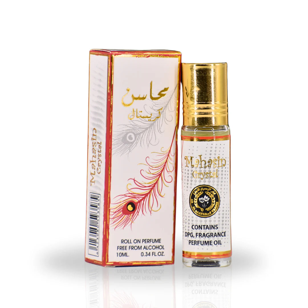 The image shows a product named "Mahasin Crystal," which is a roll-on perfume oil by Ard Al Zaafaran. The product is contained in a small 10 ml (0.34 fl. oz.) glass bottle with a golden cap. The bottle and its accompanying box feature a white design with gold and red accents, including an elegant feather pattern.