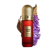 This image features a tall, cylindrical perfume bottle with a gold cap, labeled "Mexican Tobacco" by Ibraheem Al Qurashi. The bottle is red with a vertical gradient, and the volume is indicated as "100 ml / 3.4 fl.oz." Beside the bottle is a spray of purple flowers and a dry tobacco leaf, likely representing the fragrance's notes.