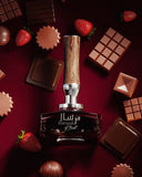 A sumptuous display featuring the Mirsaal of Trust EDP 90ml perfume bottle, surrounded by an array of chocolate pieces and fresh strawberries on a rich maroon background. The bottle, with its dark glass and wood-textured cap, stands at the center, its label showcasing the name in Arabic and English script. The composition of the image, with the indulgent treats around the elegant bottle, evokes the perfume's luxurious and sensuous character.