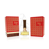 The image shows the Mirsaal "With Love" perfume by Afnan Perfumes, positioned between its two packaging boxes. The perfume bottle has a clear, angular base with a golden neck and a wooden cap, conveying an elegant design. The boxes feature a red floral arabesque design with golden borders and text, which includes the product name in both Arabic and English. The presentation is luxurious and suggests a rich, romantic fragrance within a beautifully crafted package, perfect for a sophisticated gift.