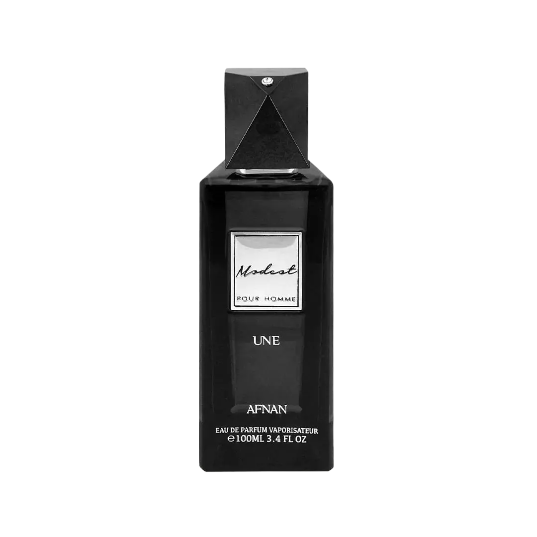 The image is of a black perfume bottle for "Modest UNE" by Afnan Perfumes. The bottle has a sleek, rectangular shape with a black cap and a diamond-like embellishment on the top. The label on the bottle is white with black lettering that reads "Modest" in cursive script and "POUR HOMME" below it in capital letters, indicating that it is a fragrance for men.