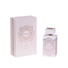 The image shows a bottle of "Musk Is Great" extrait de parfum by Noya alongside its packaging. The perfume bottle is rectangular and white with intricate geometric designs in a metallic rose gold color. It has a distinctive, square-shaped cap with vertical ridges and a rose gold accent at the base. The front of the bottle features a circular label with the text "Musk Is Great" and the brand name "Noya." The matching packaging box is also white with metallic rose gold geometric patterns.